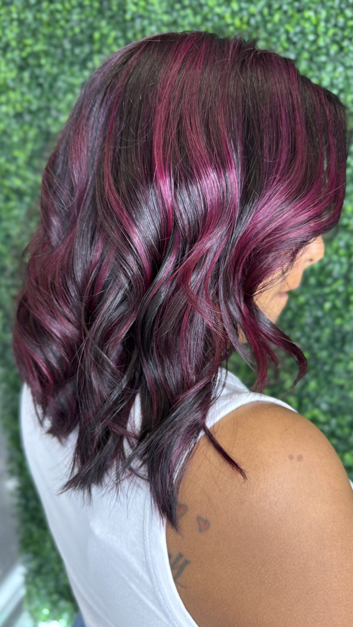 Dark hair with burgundy and magenta highlights in loose waves, seen from behind