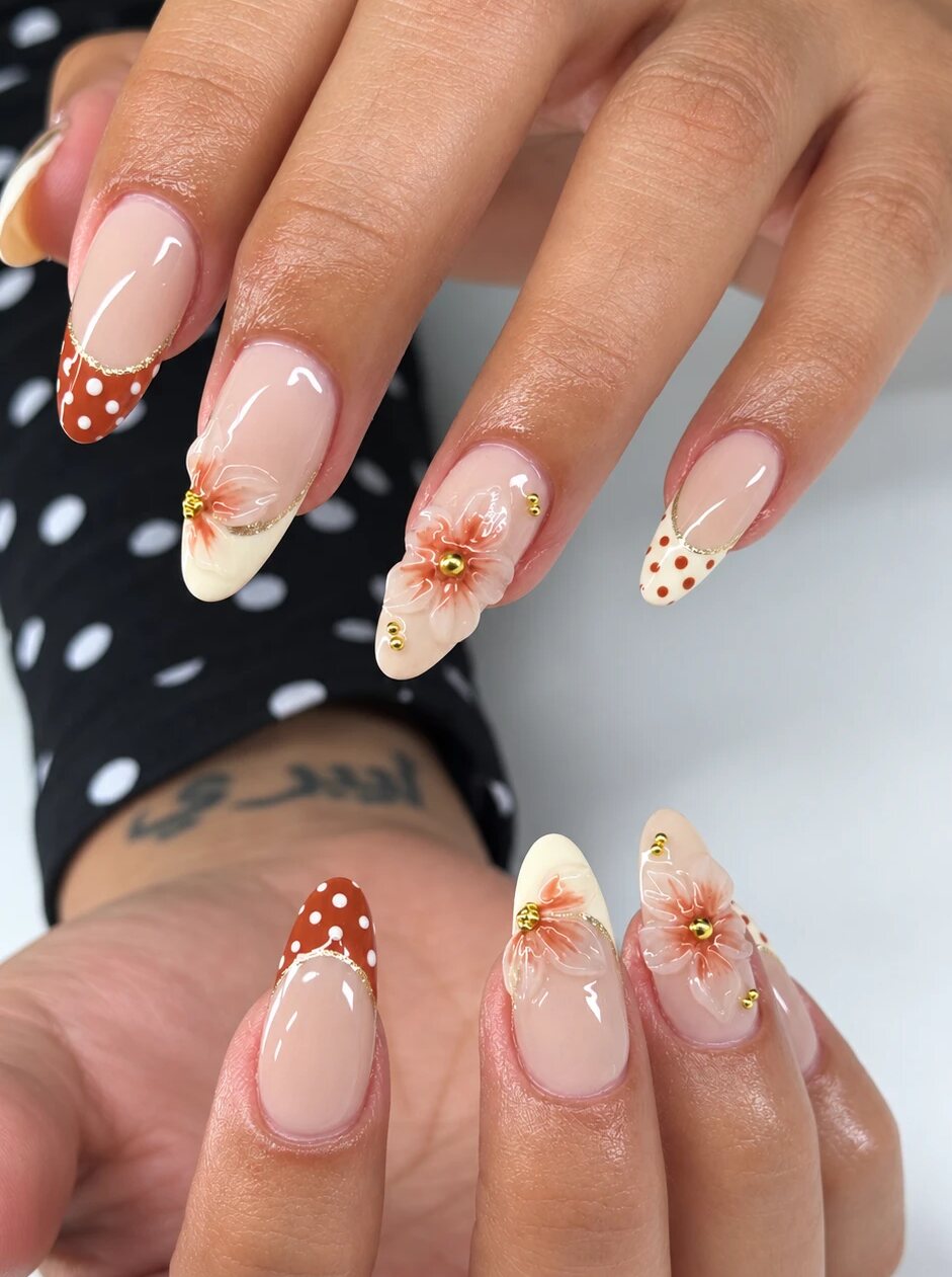 Almond nails with a nude base, hand-sculpted terracotta flowers, polka-dot tips and gold beads